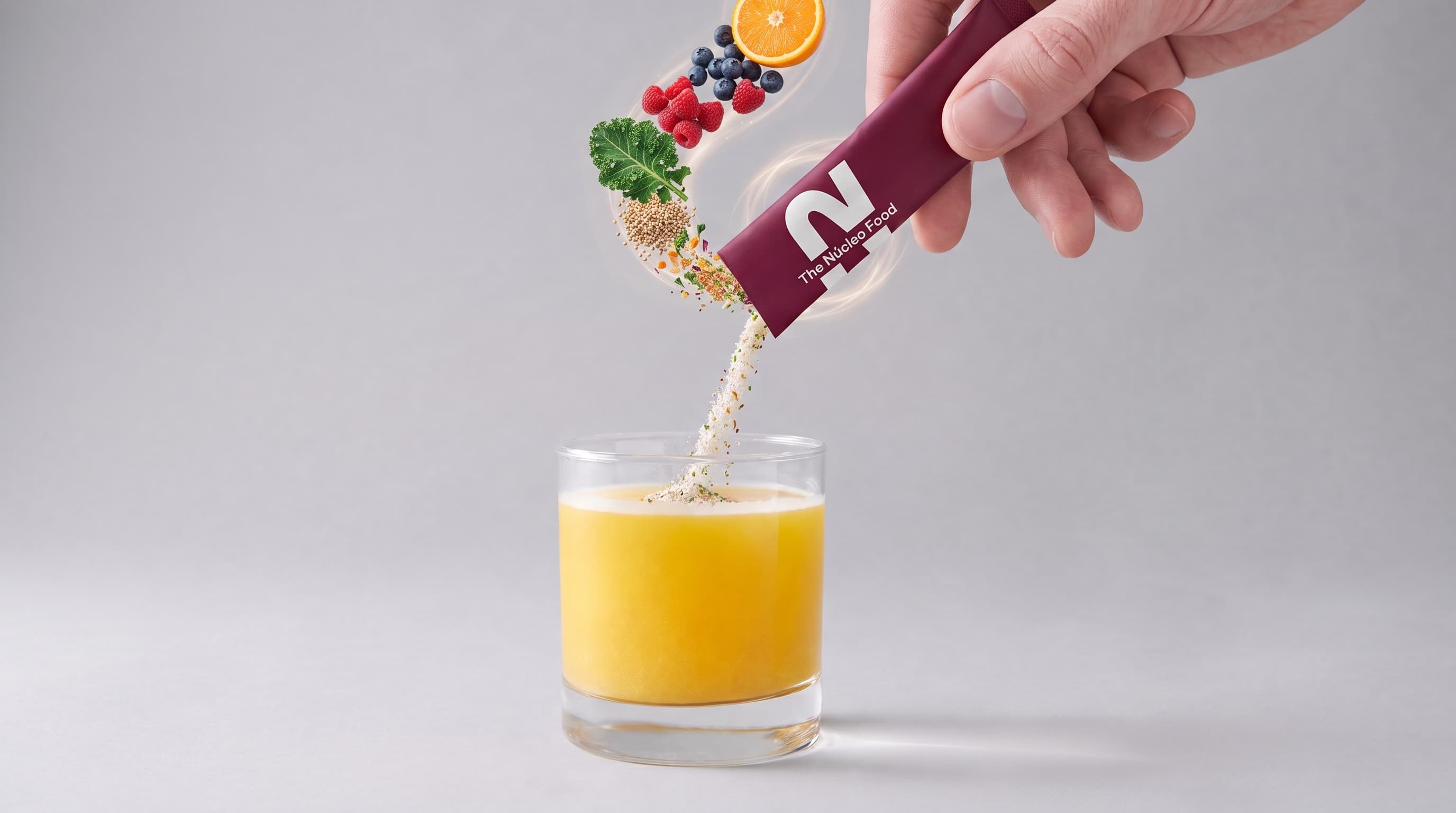 Stick de The Nucleo Food vertiendo polvo con frutas e ingredientes funcionales sobre un vaso de jugo